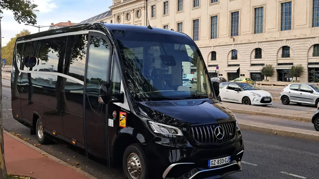 Minibus Mercedes Sprinter noir à l’arrêt le long d’un quai lyonnais, devant une façade en pierre