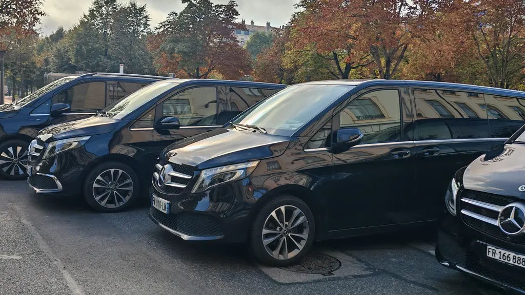 Trois Mercedes Classe V noires alignées sur un parking, sous les arbres d’automne