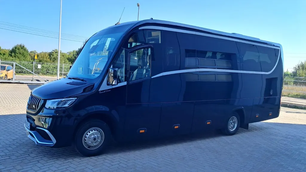 Grand minibus Mercedes Sprinter à carrosserie sombre, vu de trois quarts avant au soleil