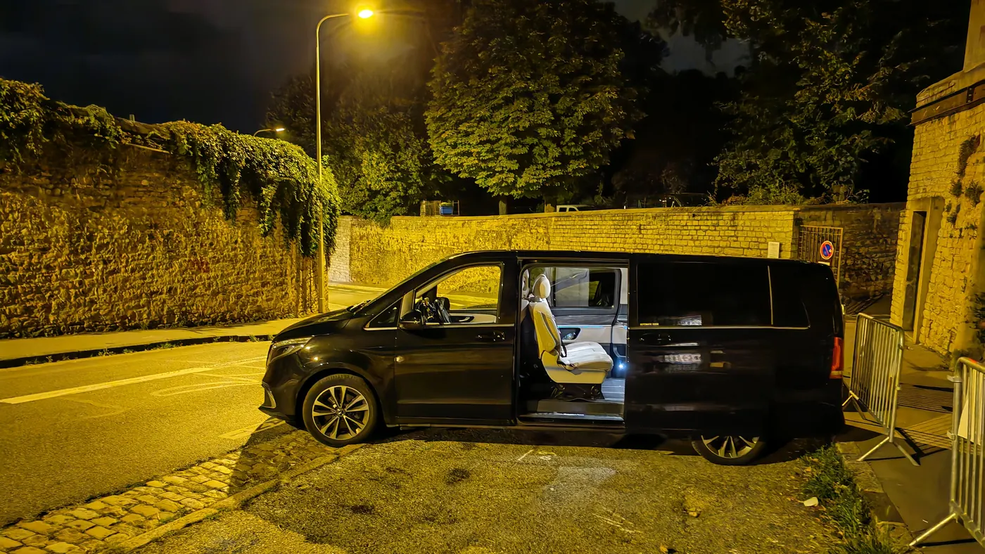 Mercedes Classe V noire de profil sous un lampadaire, porte latérale ouverte sur l’habitacle éclairé