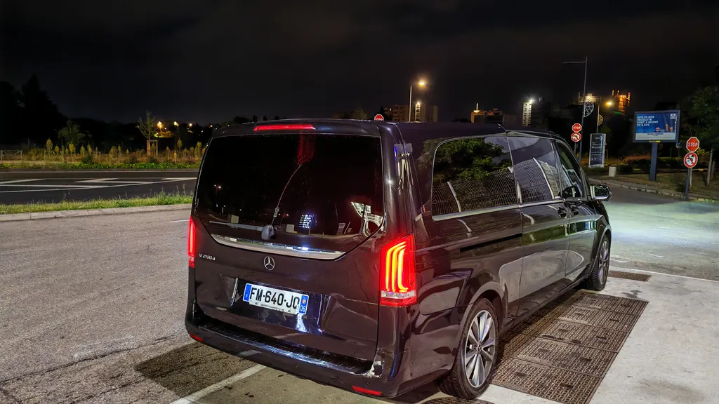 Mercedes Classe V noire vue de trois quarts arrière la nuit, feux allumés